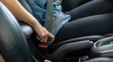 Asyalı kadın emniyet kemerini arabaya takıyor.