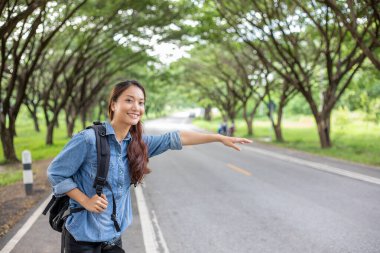 Araba bekleyen Asyalı kadın turistler ve gezginler ve yol kenarında kollarını açmış duran Özgürlük yolcusu kadın..