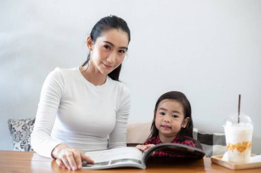 Asyalı anneler kızlarına tatillerde evde kitap okumayı öğretiyor. Ailenin eğitim kavramları ve faaliyetleri