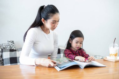 Asyalı anneler kızlarına tatillerde evde kitap okumayı öğretiyor. Ailenin eğitim kavramları ve faaliyetleri