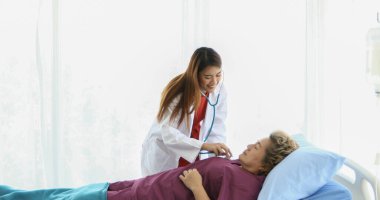 Doktor, hastanedeki yaşlı bir kadına ilaçlarını açıklıyor.