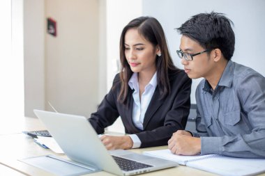 Asyalı işadamları ve grup iş ortakları için not defteri kullanıyor toplantıda belgeler ve fikirler tartışıyorlar ve iş kadınları mutlu bir şekilde gülümsüyorlar. 