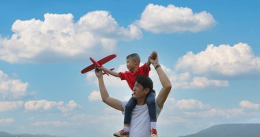 Baba ve oğul gün batımında çayırda oyuncak uçak oynuyorlar. Mutlu duygularla. Aile, Tatil ve Seyahat konsepti.