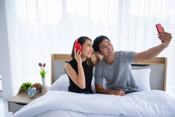 Asyalı Çift Aşıklar Cep Telefonlarıyla Oynuyorlar Evde Yatakta Selfie Çekiyorlar — Stok fotoğraf