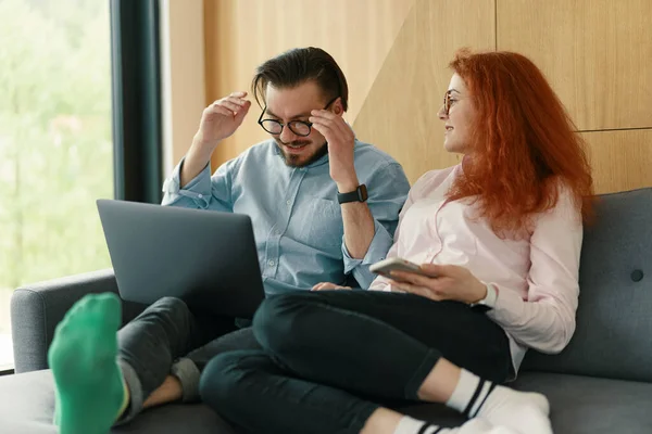 Vrolijk liefdevol jong paar met behulp van laptop en het analyseren van hun financiën met documenten — Stockfoto