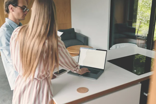 Zijaanzicht van de familie paar van het bedrijf op de kithcen met laptop mockup — Stockfoto