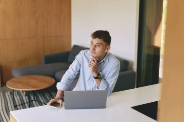 Bilgisayarlı ve akıllı telefonlu bir iş adamının evde çalışmasını ön planda görmek