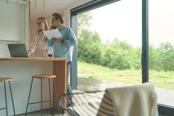 Uitzicht vanuit de verte van familie paar van het bedrijfsleven op de keuken met laptop — Stockfoto