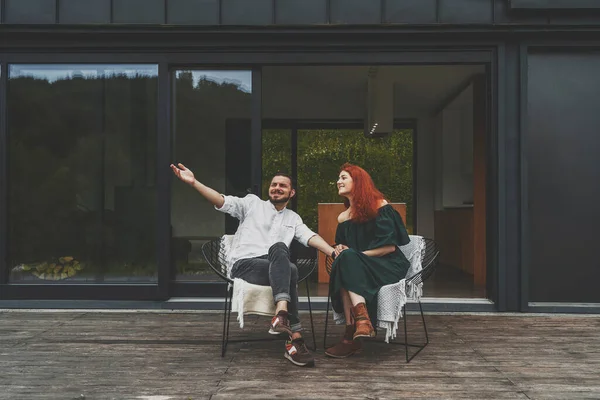 Gelukkig gezin zittend buiten op het terras van groot landhuis — Stockfoto