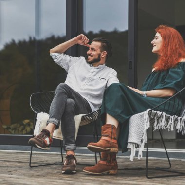 Gülümseyen bir çift turist dağlarda, terasta tatil yapıyor.