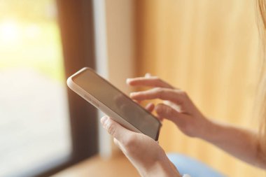 Boş beyaz masaüstü ekran ile akıllı telefon tutan bir kadının yan görünümü