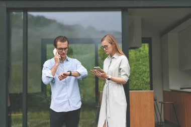 Terasta akıllı telefonlarla çalışan milenyum çiftlerinin ön görüntüsü.