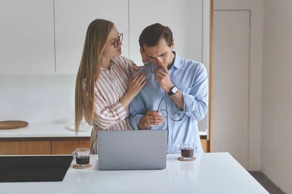 Vooraanzicht van jong echtpaar staand op de keuken met koffie en laptop — Stockfoto