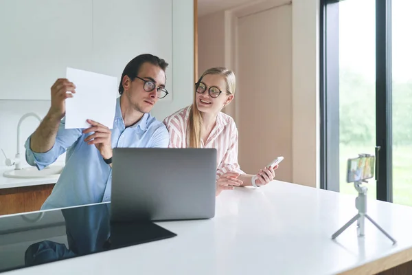 Knappe man met bril die documenten analyseert terwijl hij thuis met assistent zit — Stockfoto