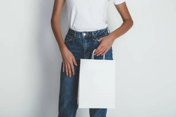 Девушка в белой футболке и с белым пакетом в руках — стоковое фото
