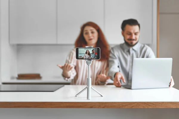 Young family couple recording video content at smartphone and tripod