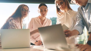 Front view of employees group discussing project at laptop