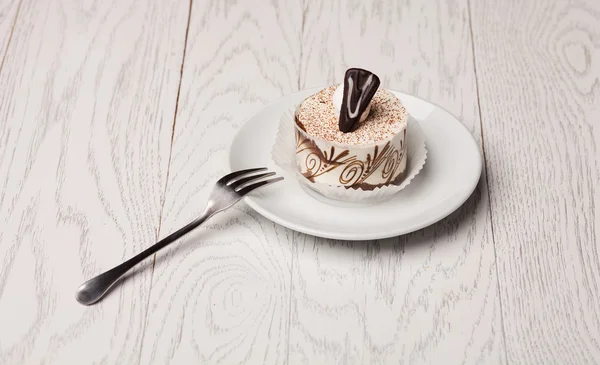 Sweet cake at plate on wooden table — Stock Photo, Image