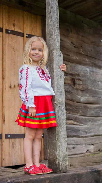 Little ukrainian girl standing near old national wooden house — Stock Image Little ukrainian girl standing near old national wooden house Stock Photo