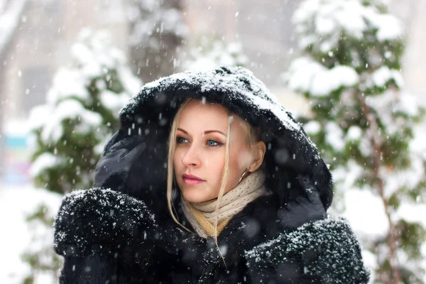 Girl in the black coat under snow fall - close up portrait — Stock Photo, Image
