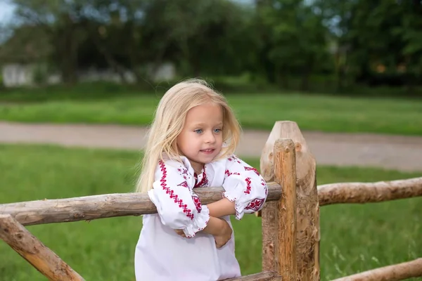 Petite fille en vêtements traditionnels ukrainiens sur la haie — Photo