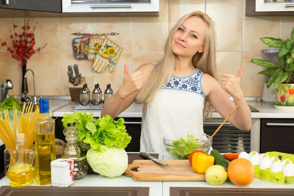 Donna con due mani pollice in alto al tavolo della cucina Fotografia Stock