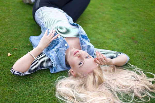 Beautiful lying on the green grass with untressed hair — Stock Photo, Image