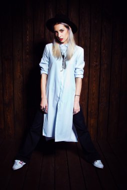 Trendy Hipster kız koyu ahşap duvar arka plan ayakta