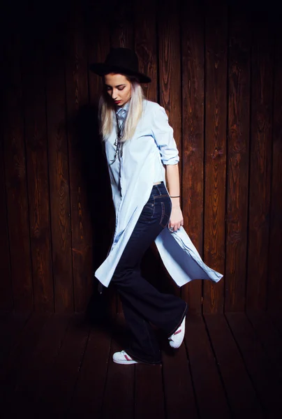 Menina Hipster na moda em pé no fundo da parede de madeira escura — Fotografia de Stock