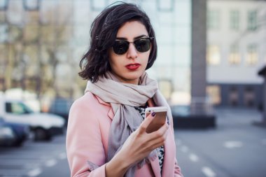 Genç kadın güneş gözlüğü ile telefon