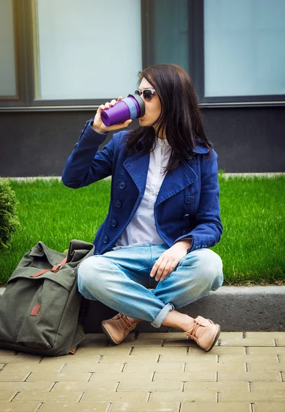 草の上に座って、コーヒーを飲みながら、学生の女の子 — ストック写真