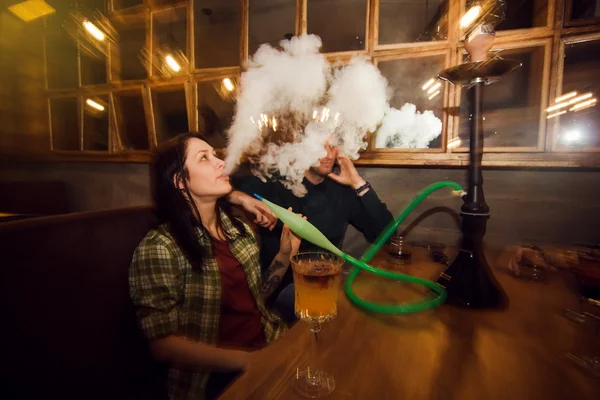 Hermosa pareja fumando narguile en el bar — Foto de Stock