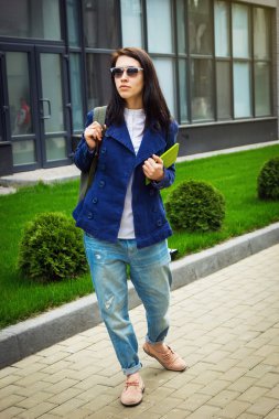 Güneş gözlüğü öğrenci kızla tablet ofis binası yakınındaki yürürken elinde