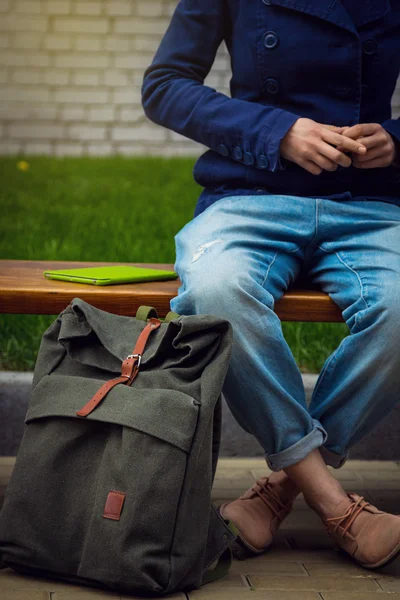 Sırt çantası ile bankta oturan öğrenci kız