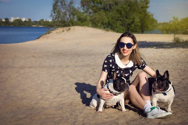 Menina bonita na praia com dois bulldogs franceses — Fotografia de Stock