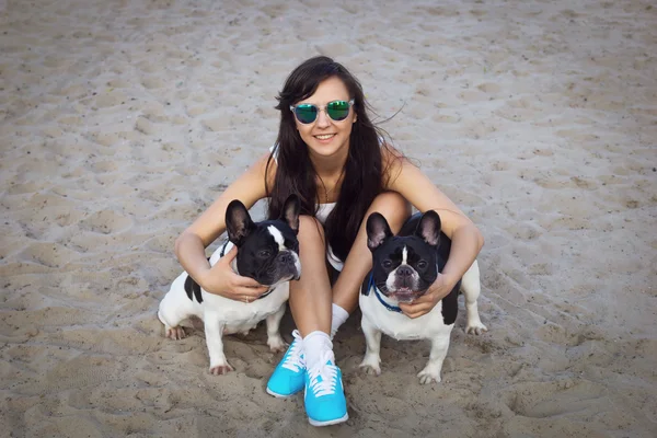 Menina bonita na praia com dois bulldogs franceses — Fotografia de Stock