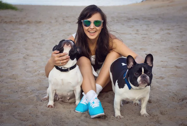 Menina bonita na praia com dois bulldogs franceses — Fotografia de Stock