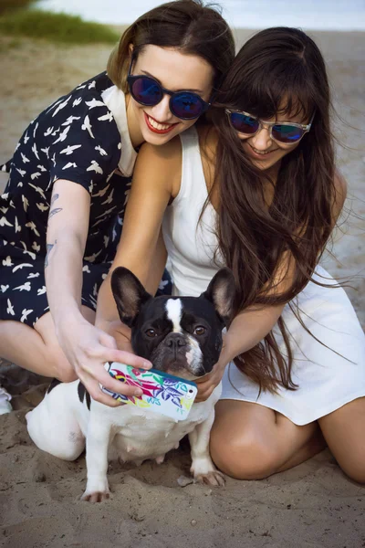 Duas belas jovens mulheres na praia tirando foto selfie com bulldogs franceses — Fotografia de Stock