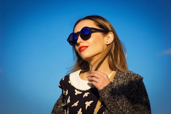 Bella giovane donna in occhiali da sole contro il cielo blu — Foto Stock