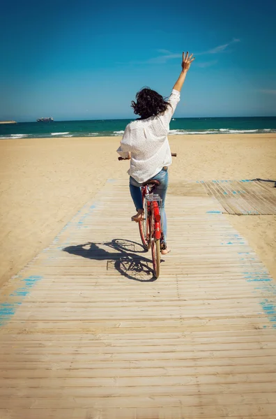 Gelukkig jonge vrouw met een fiets op een strand — Stockfoto