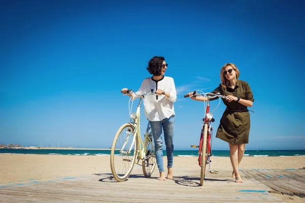 Dois amigos andando na praia com bicicletas — Fotografia de Stock