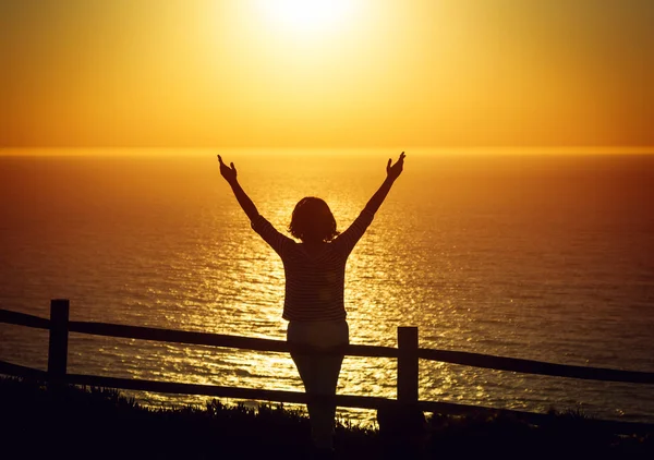 Mujer feliz abrir los brazos bajo el atardecer en la playa —  Fotos de Stock