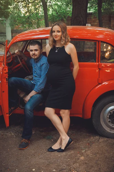 Man and pregnant woman near red car — Stock Photo, Image