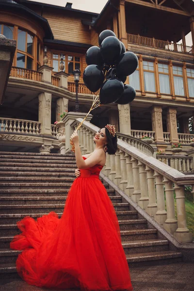 Ursnygg kvinna i röd klänning med svarta ballonger — Stockfoto