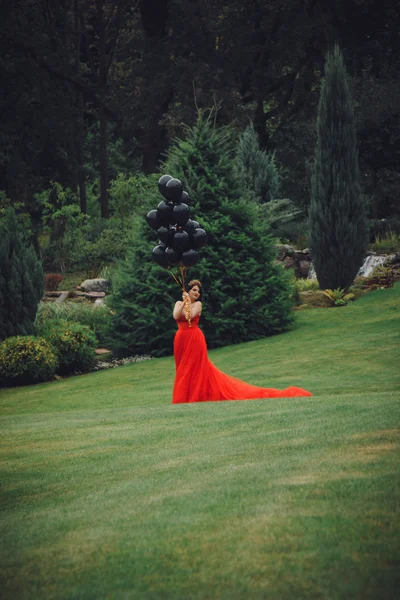 Mulher linda em vestido vermelho com balões pretos — Fotografia de Stock