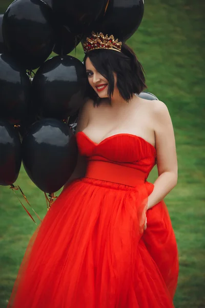 Wanita cantik bergaun merah dengan balon hitam Stok Gambar Bebas Royalti