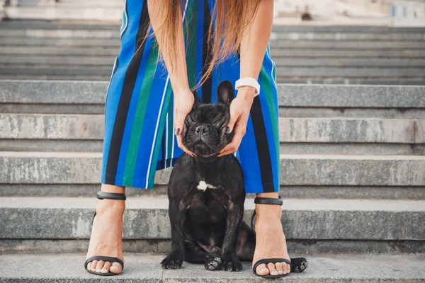 Kadın bacaklarının arasına merdivenlerde oturan siyah Fransız bulldog köpek yavrusu — Stok fotoğraf