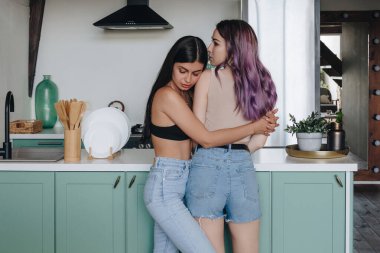 LGBT lezbiyen çifti mutfakta sarılıyor.