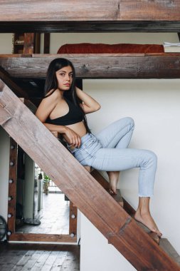 Evde kot pantolon giyen güzel genç bir kadın.