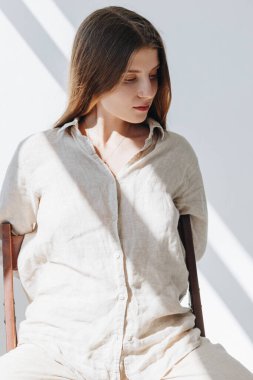 Bej keten gömlek giyen beyaz bir kadının portresi.